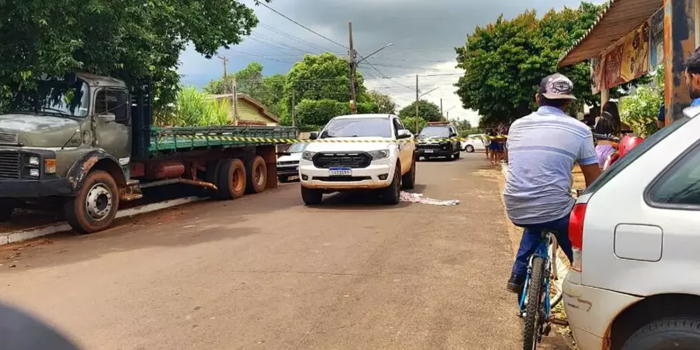 Corpo da criança embaixo da caminhonete, coberto por um lençol branco