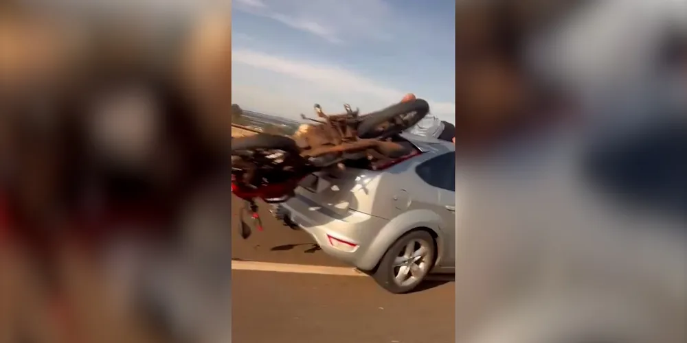 A motocicleta ficou literalmente presa ao veículo, permanecendo “encaixada” na estrutura traseira