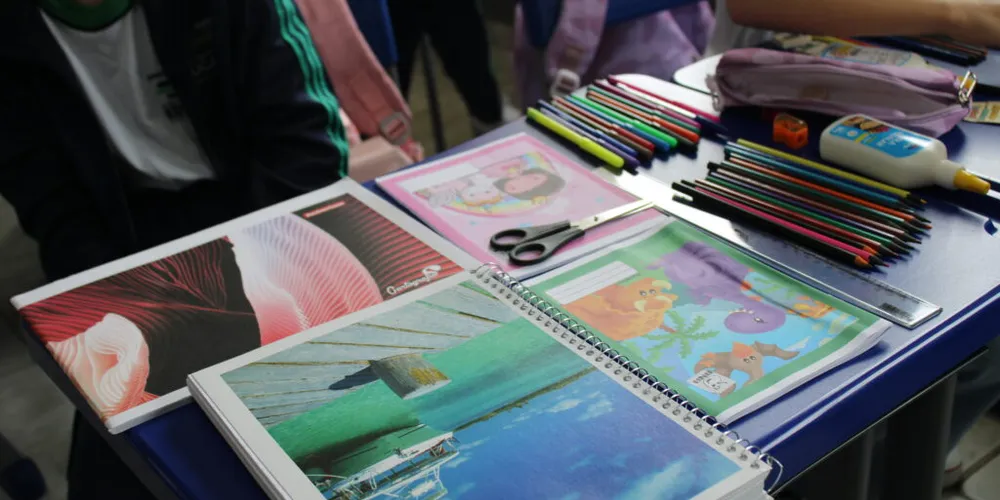 Os itens incluem tesoura, tubo de cola branca, caderno quadriculado grande, pincel, pote de glitter, lápis preto e coloridos, entre outros