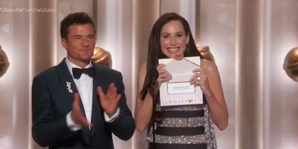 Mini Driver e Orlando Bloom anunciando 'O agente secreto' como vencedor do Globo de Ouro