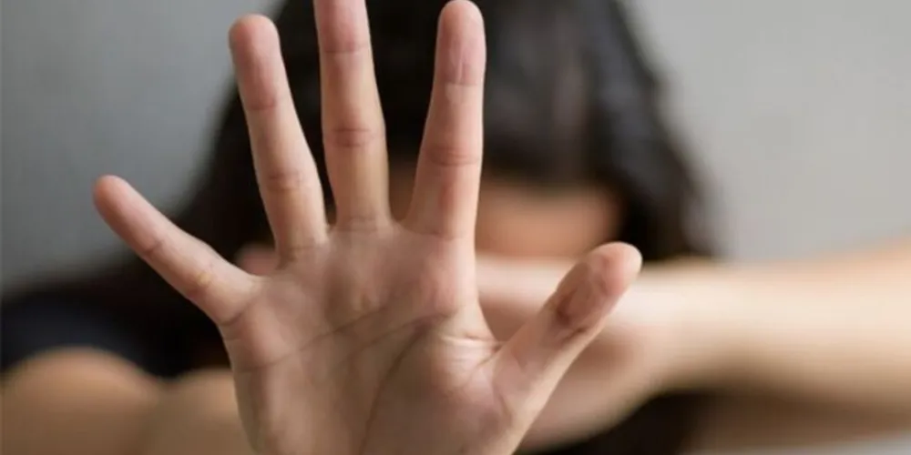Imagem ilustrativa mostra uma mulher sinalizando "pare" com a mão em campanha de combate à violência contra mulheres