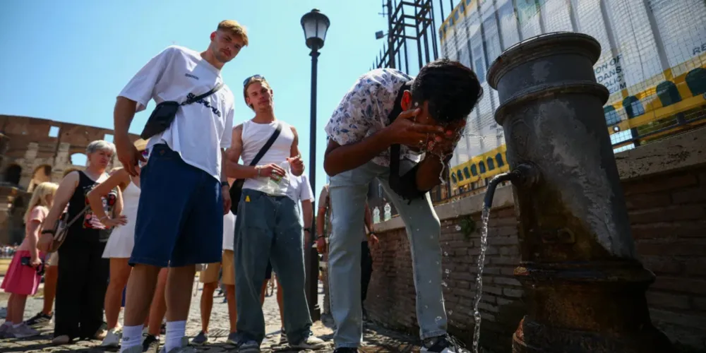 Uma pessoa se refresca em uma fonte pública próxima ao Coliseu durante uma onda de calor em Roma