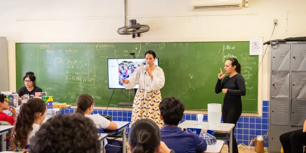 Rayssa Miranda, em pé e de preto, traduz do Português para as Libras