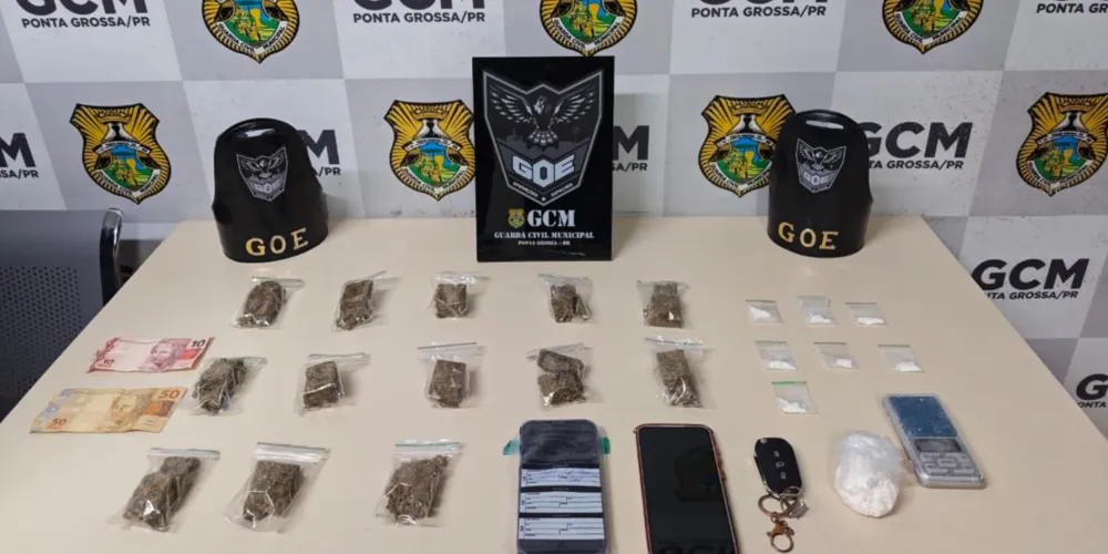Foram apreendidos porções de maconha e cocaína, uma balança de precisão, um celular e dinheiro