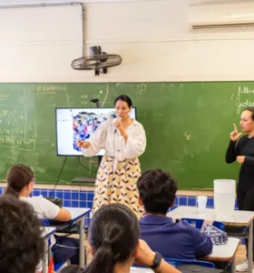 Rayssa Miranda, em pé e de preto, traduz do Português para as Libras