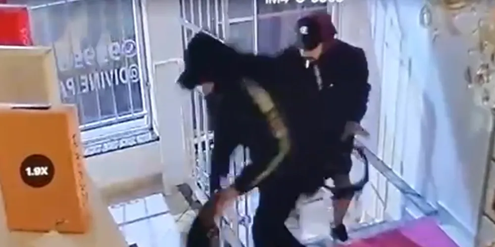 A dupla de suspeitos aparece furtando diversos perfumes na loja durante a madrugada