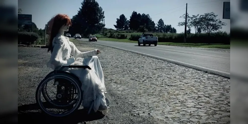 Uma noiva pálida de cabelos avermelhados e olhar fixo na estrada aparece sentada em uma cadeira, como se aguardasse a passagem dos caminhoneiros