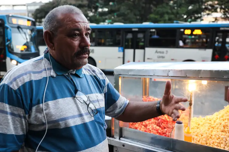 Enquanto vende pipoca, Gil Lopes usa os fones para ouvir mensagens dos filhos