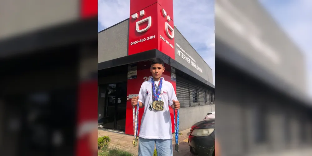 Cauã posa com suas medalhas na fachada da Dbug