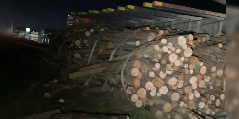 O caminhão com carga de madeira tombou na pista