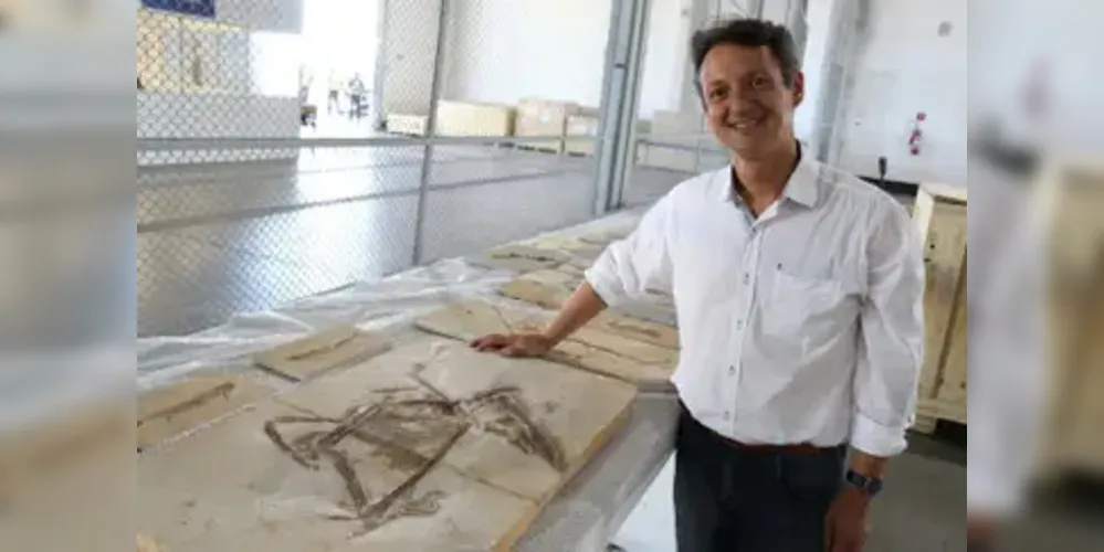 Professor Allysson Pinheiro ao lado do fóssil do dinossauro Ubirajara