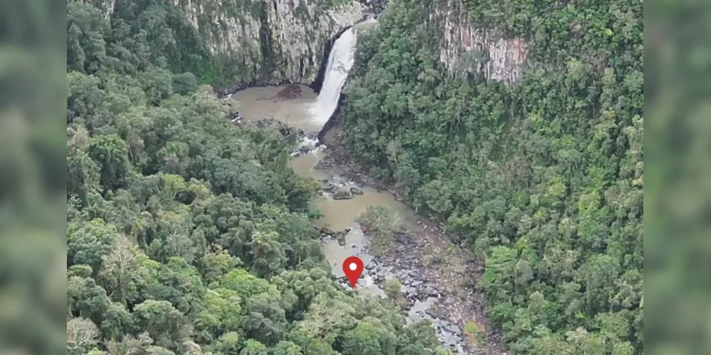 Imagem aérea mostra o ponto aproximado onde o corpo de Ana Paula Silveira Cardoso foi encontrado, em Sapopema (PR). O marcador vermelho indica a localização no rio, abaixo da queda d’água e do Poço Preto, onde o drone a indicou nesta quinta-feira