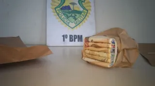 Cédula é dobrada em meio a pedaços de papel para que pareça se tratar de um maço de dinheiro