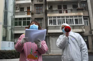 Os trabalhadores comunitários verificam as informações dos residentes no distrito de Jiangan, em Wuhan, província de Hubei, na China Central Wuhan, o epicentro do novo surto de coronavírus