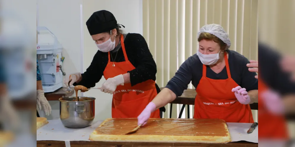 Três voluntárias trabalham na produção do bolo