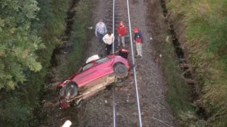 O carro caiu em cima da linha férrea que passa pelo local.